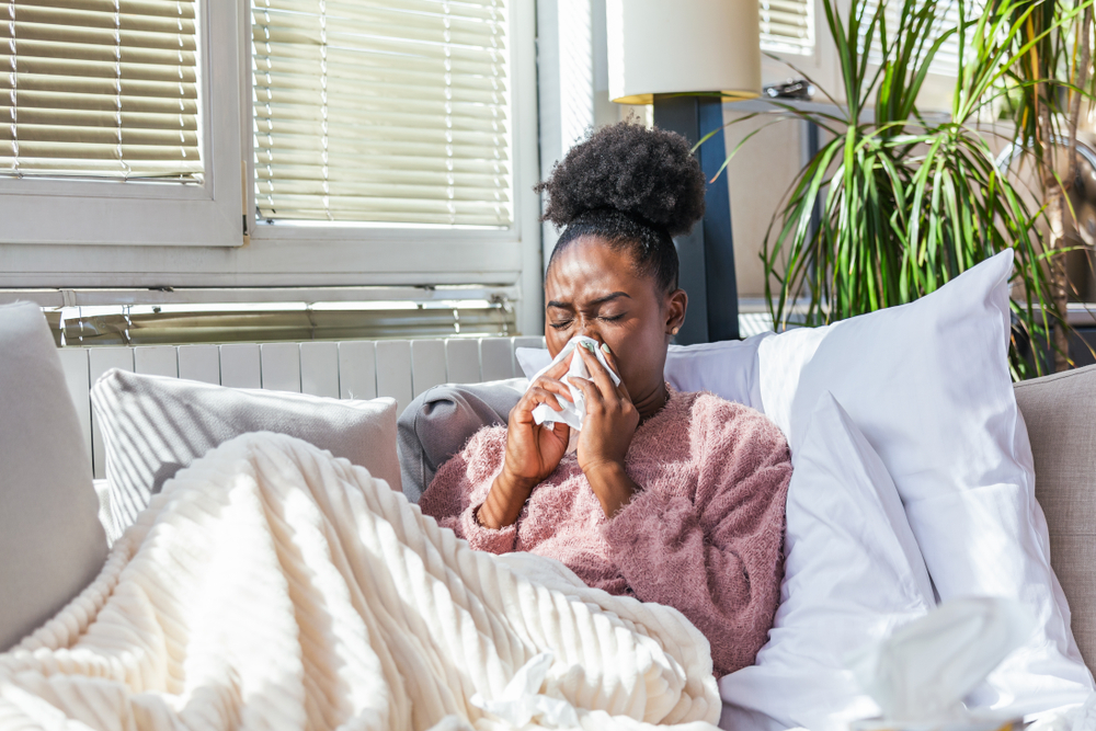 sick woman experiencing sinus issues blowing her nose.
