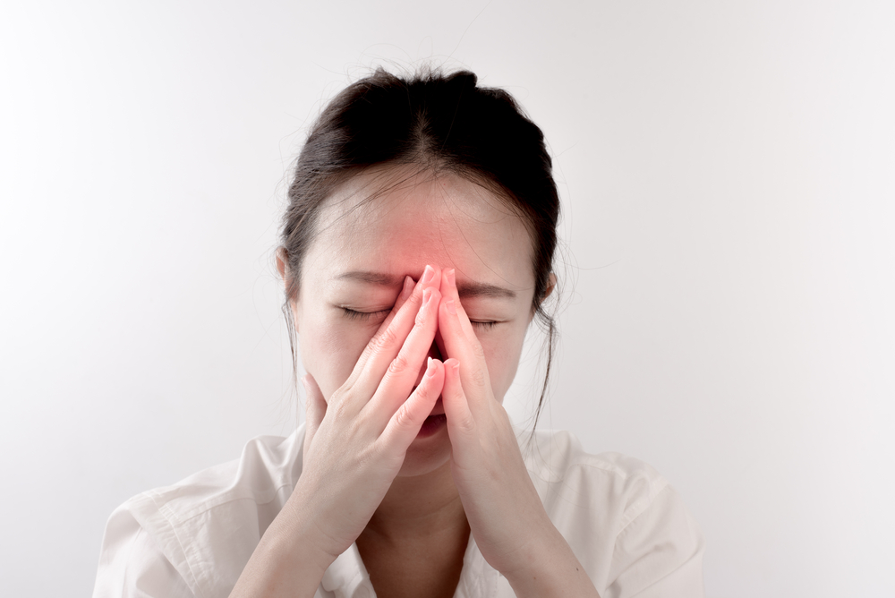 woman holding nose due to sinus pain.