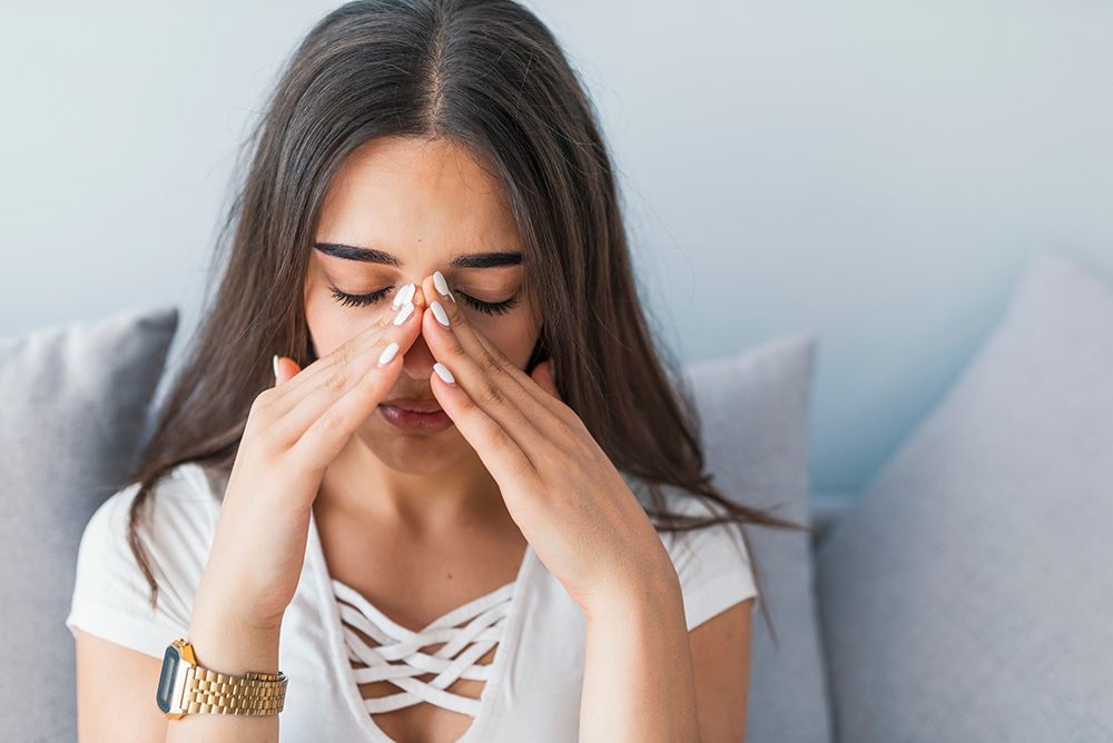Sad woman holding her nose and head because sinus pain